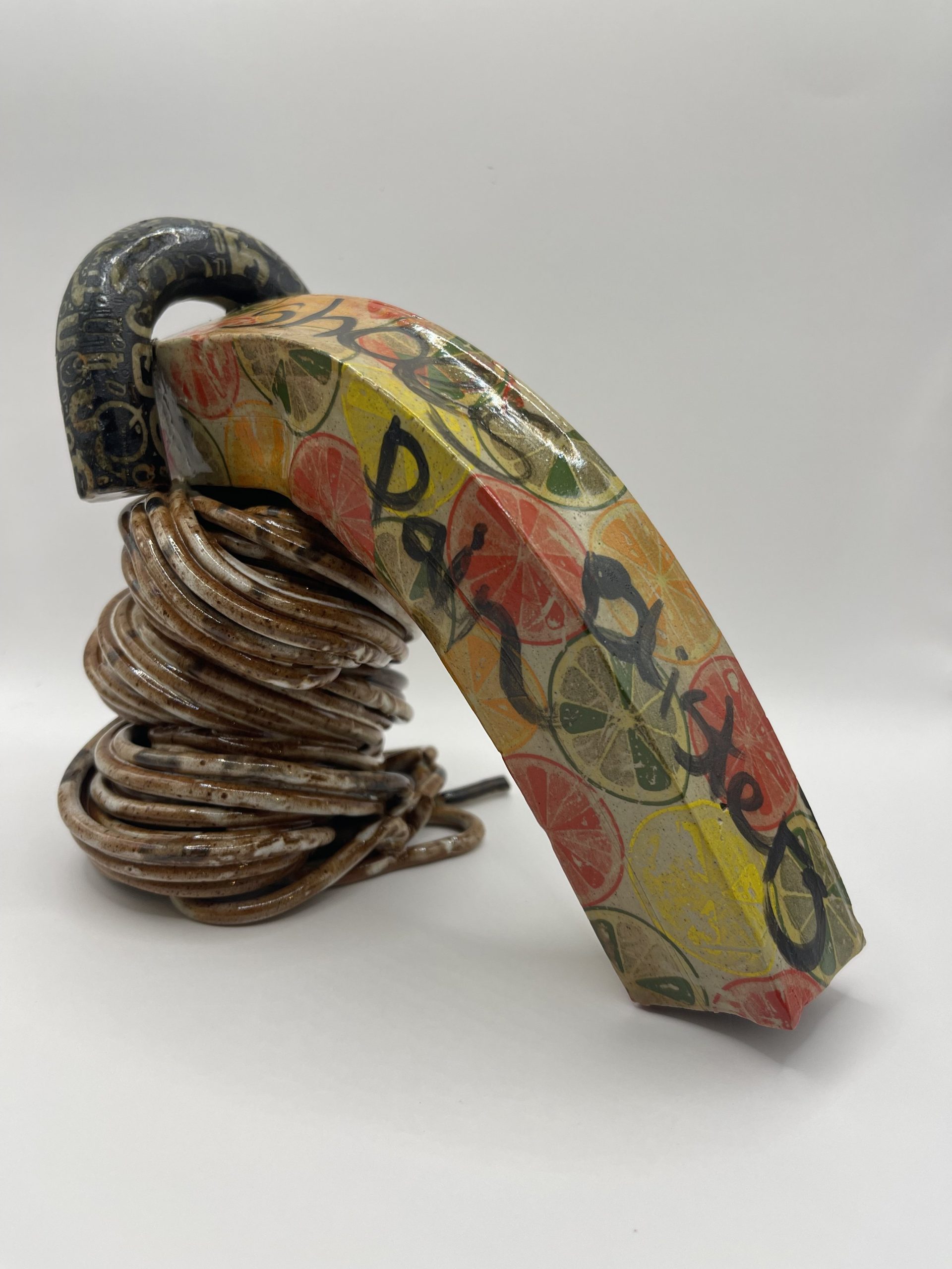  Extruded white stoneware clay decorated with decals , underglaze and free hand writing. I was trying to add humour to this design with bright colours but used the black lettering to draw attention to the pain and discomfort high heels can cause. 