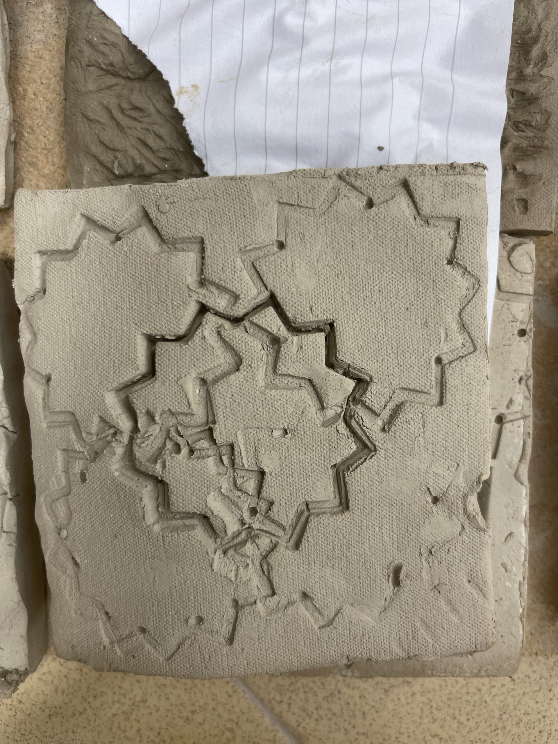  Using a soft clay tile I used a plastic shape cutter to create a symmetrical but overlying pattern that created an unbalanced mechanical texture. 